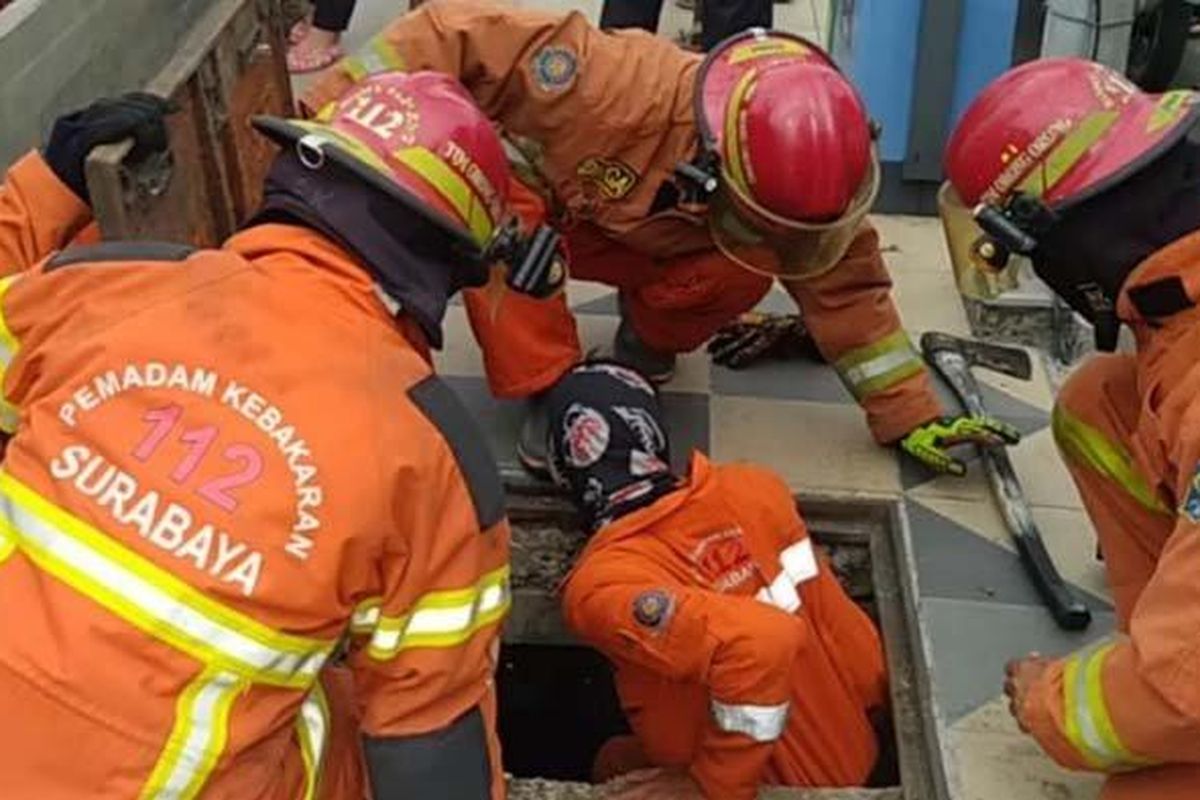 Sejumlah petugas pemadam kebakaran (Damkar) Kota Surabaya menyelamatkan seekor anak kucing terjebak saluran air di kawasan Balai Pemuda Surabaya, Jumat sore (10/9/2021). 
