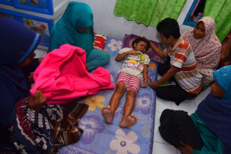 Seorang anak kecil yang selamat tertimbun reruntuhan rumah yang ambruk akibat gempa bumi dirawat oleh keluarganya di Desa Sumelap, Kota Tasikmalaya, Jawa Barat, Sabtu (16/12/2017). Gempa berkekuatan 6,9 skala richter dan berpotensi tsunami dilaporkan terjadi pada Jumat (15/12) pukul 23:47:58 WIB di wilayah Tasikmalaya. 