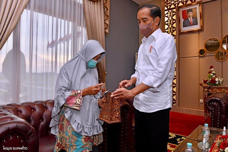 Presiden Joko Widodo saat memberikan bantuan kepada Mak Unah di ruang VIP Bandara Internasional Sultan Mahmud Badaruddin Palembang, Senin (24/1/2022).