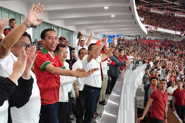 Presiden Joko Widodo mengangkat tangan menirukan gerakan suporter.

