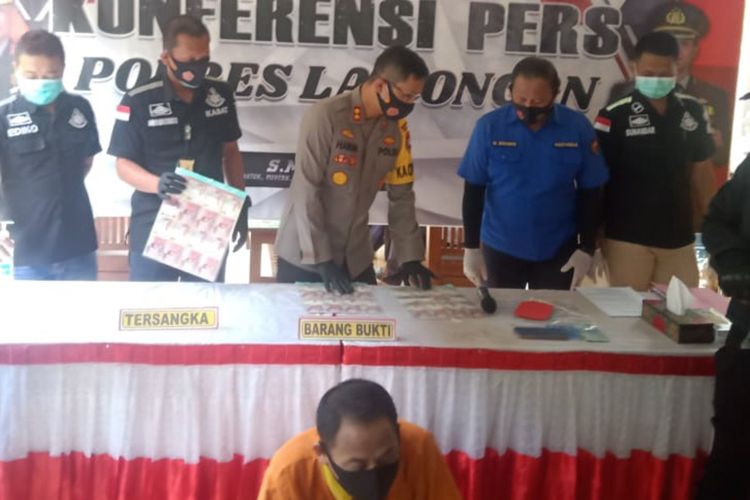 Polisi saat menunjukkan barang bukti uang palsu dan pelaku dalam rilis pengungkapan kasus di Mapolres Lamongan, Rabu (14/10/2020).