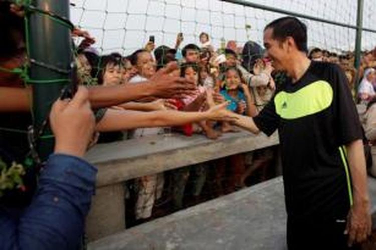 Gubernur DKI Jakarta dan juga Calon Presiden terpilih Joko Widodo alias Jokowi bersalaman dengan warga seusai bermain bola di acara Pesta Rakyat Waduk Pluit, di Lapangan Bola Waduk Pluit, Jakarta Utara, Minggu (17/8/2014). Selain bermain bola, Jokowi juga sempat ikut serta dalam lomba balap karung bersama warga di Taman Waduk Pluit. 