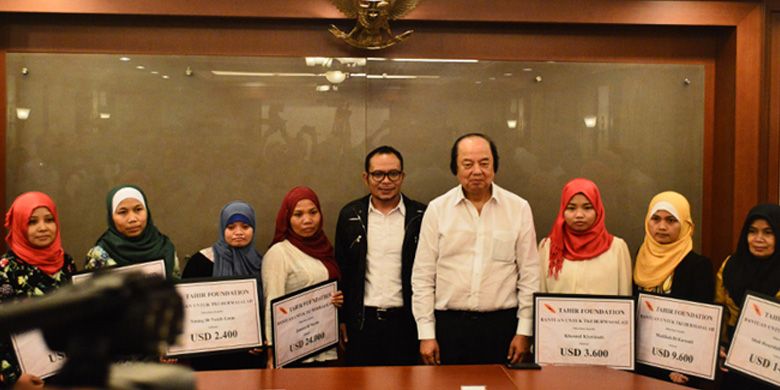 Menteri Tenaga Kerja dan Transmigrasi, Muhammad Hanif Dhakiri (jaket hitam) bersama dengan Pengusaha Sri Tahir (kemeja putih) memberi bantuan kepada 12 tenaga kerja Indonesia yang berhasil dipulangkan dari Yordania di Kementerian Tenaga Kerja dan Transmigrasi, Jakarta, Kamis (7/9) malam.