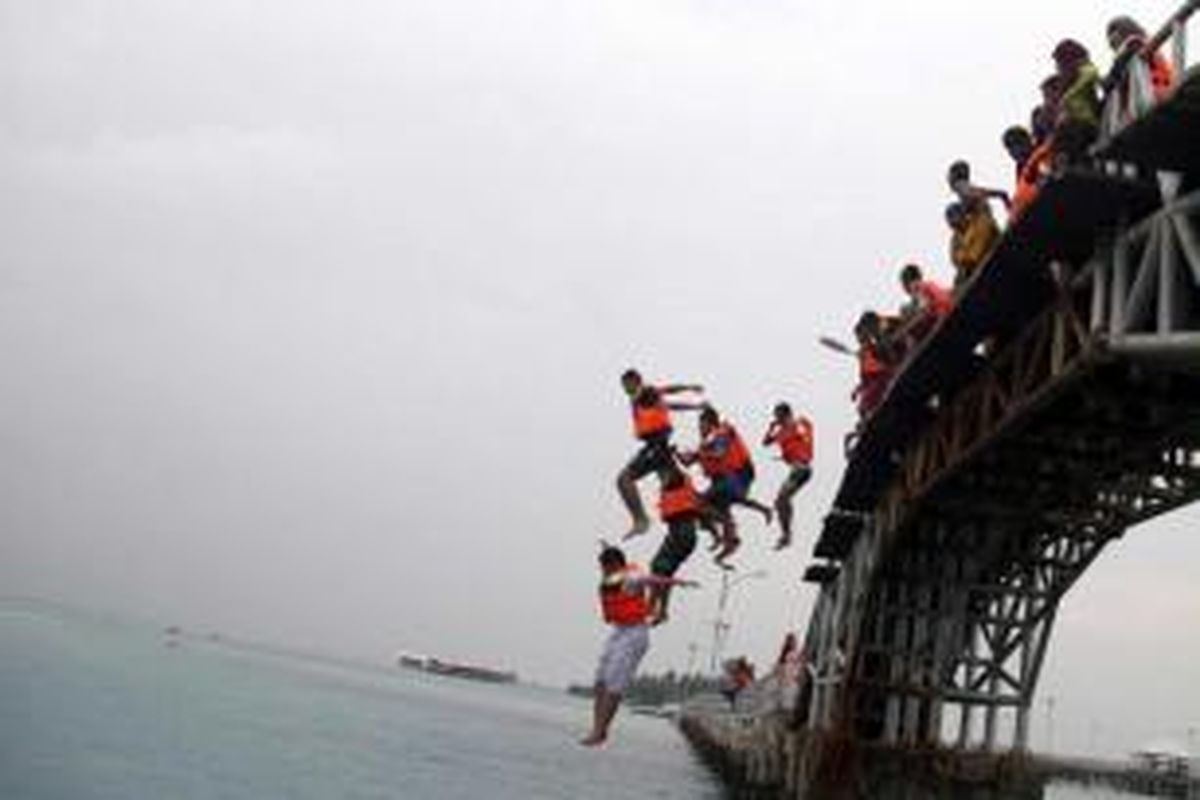 Para wisatawan melompat dari Jembatan Cinta yang menghubungkan Pulau Tidung Kecil dengan Pulau Tidung Besar, Kepulauan Seribu, Selasa (14/5/2013). Pulau Tidung merupakan salah satu alternatif wisata bahari yang terdapat di Ibu Kota Jakarta.