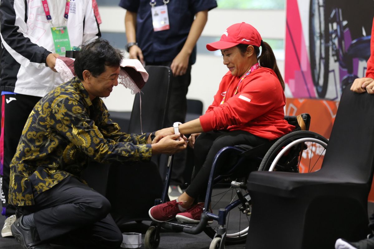 Hirokazu Satoh, Chief Representative Casio Singapore Pte, Ltd, Jakarta Representative Office berlutut memasangkan sebuah jam tangan Baby-G untuk atlet paracycling Indonesia Ni Kadek Karya Dewi, di Jakarta, Rabu (3/10/2018).