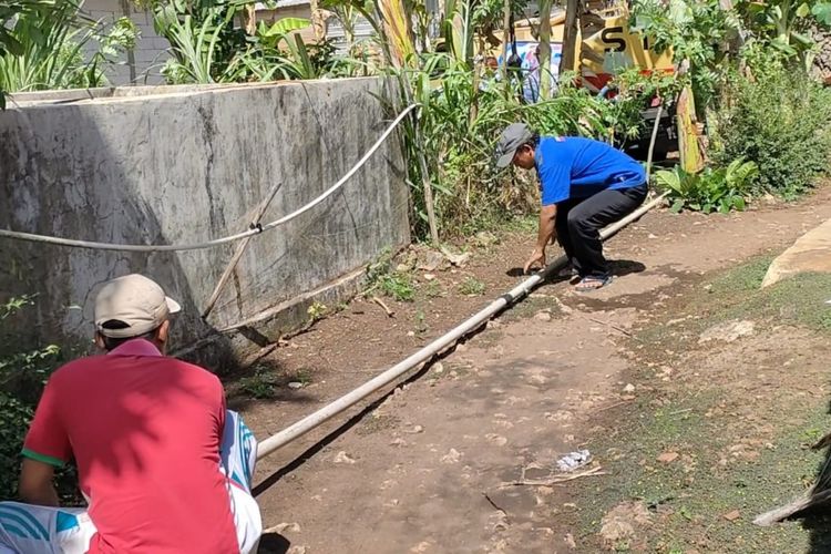 Warga memasang pipa saat membeli air dari tangki swasta di Kapanewon Panggang, Gunungkidul 