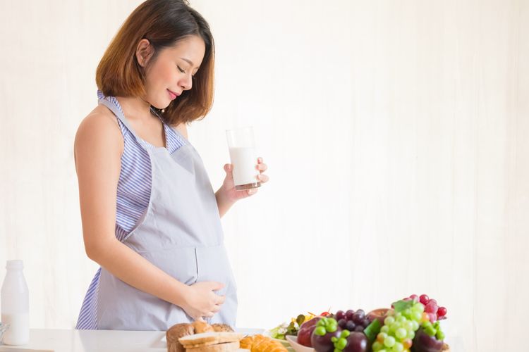Ilustrasi ibu hamil sedang mengonsumsi makanan dan minuman berbutrisi.