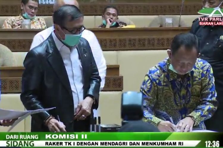 Menteri Dalam Negeri Tito Karnavian bersama Menteri Hukum dan HAM Yasonna Laoly menandatangani draf Perppu tentang Pilkada di Kompleks Parlemen, Senayan, Jakarta, Selasa (30/6/2020).