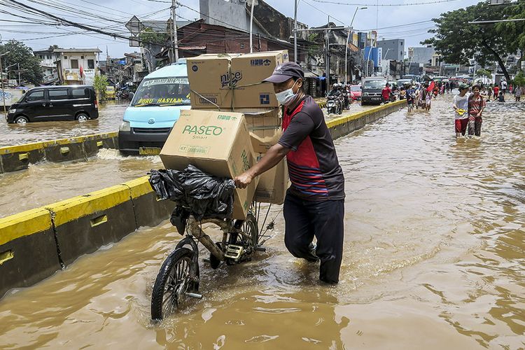 Seorang warga mengangkut barang menggunakan sepeda saat melintasi banjir di Jalan Jatinegara Barat, Kampung Pulo, Jakarta, Sabtu (20/2/2021). Intensitas hujan yang tinggi serta buruknya drainase menyebabkan banjir di sejumlah wilayah Jakarta.