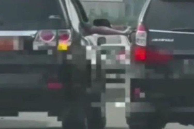 Tangkapan layar rekaman video viral pengemudi mobil berpelat dinas saat menodongkan senjata api kepada pengendara mobil pribadi di Tol Jagorawi, Minggu (18/9/2022).