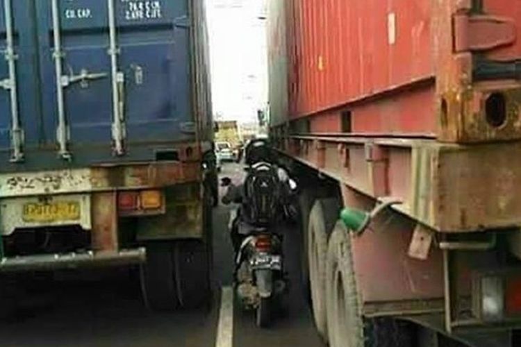 Waspada berkendara di antara truk besar.