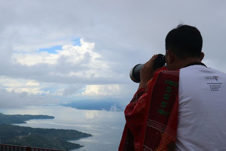 Pengunjung sedang menikmati pemandangan Danau Toba dengan teropong bintang di Huta Ginjang di Kabupaten Tapanuli Utara