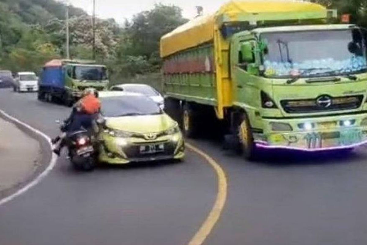 Tangkapan layar video yang menampilkan mobil Toyota Yaris menabrak pengendara sepeda motor ketika sedang menyalip di tikungan.