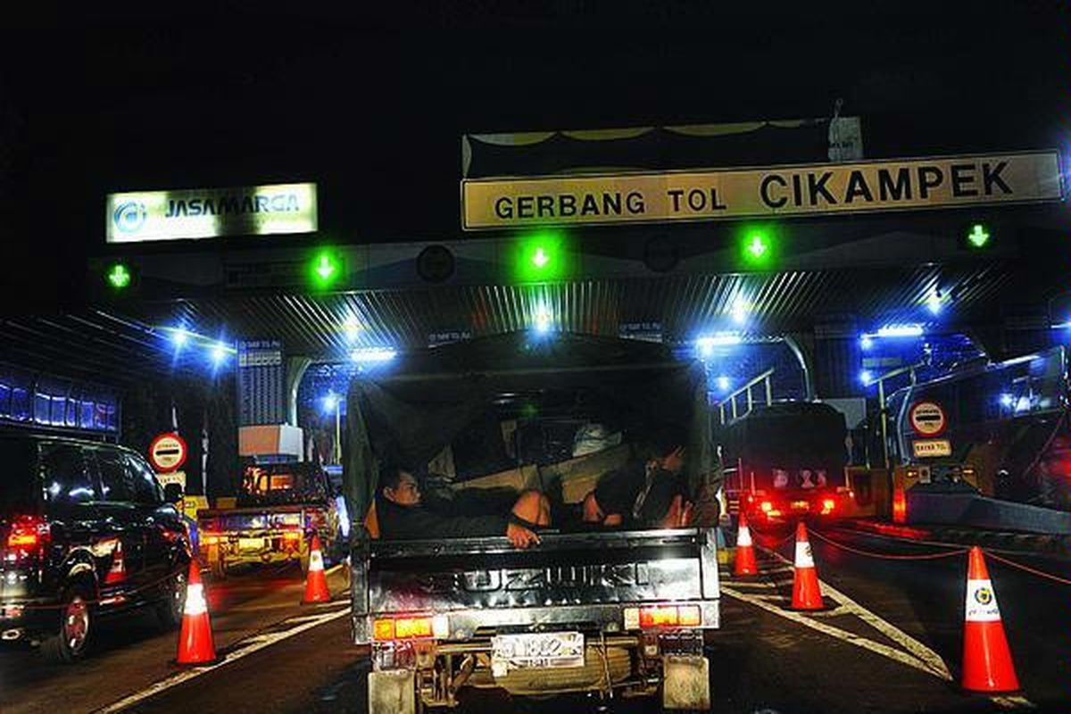 Pemudik dengan kendaraan bak terbuka yang telah dimodifikasi antre untuk keluar dari Pintu Tol Cikampek, Purwakarta, Jawa Barat, Minggu (12/8) malam. Kendati gelombang pemudik mulai terlihat, arus lalu lintas di jalan tol tersebut masih lancar.