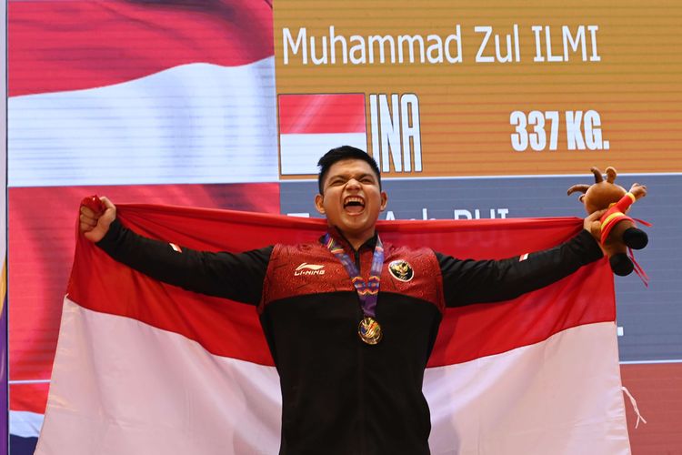 Lifter Indonesia Muhammad Zul Ilmi membawa bendera Merah Putih usai pengalungan medali nomor 89 kilogram angkat berat SEA Games 2021 Vietnam di Hanoi Sports Training Centre, Hanoi, Vietnam, Minggu (22/5/2022). Zul Ilmi meraih medali emas setelah terbaik dalam total angkatan 337 kilogram.