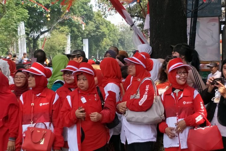Ibu-ibu memakai seragam dan menempel stiker bendera merah putih dan bendera negara peserta Asian Games 2018 untuk menyemarakkan torch relay atau pawai obor Asian Games di Jalan Raya Rawa Bambu, Jakarta Selatan, Rabu (15/8/2018).