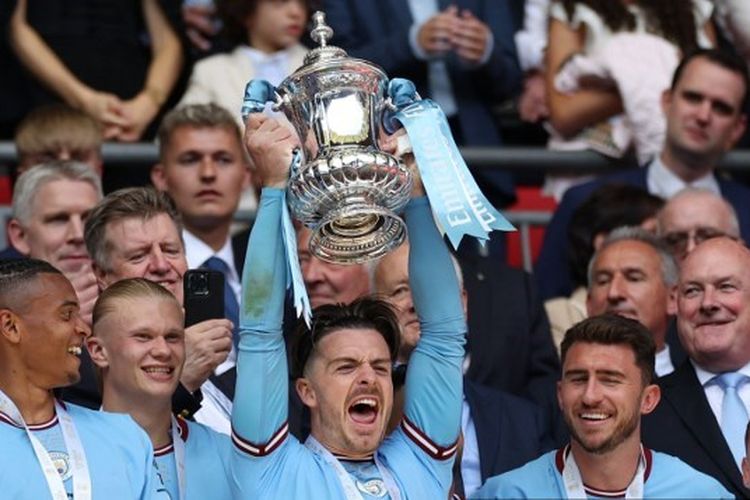 Gelandang Manchester City, Jack Grealish, saat mengangkat trofi Piala FA 2022-2023 seusai mengalahkan Manchester United di Stadion Wembley pada 3 Juni 2023. (Foto oleh Adrian DENNIS / AFP).