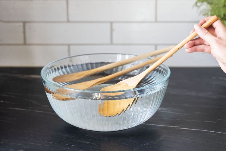 Ilustrasi cara membersihkan alat makan berbahan kayu menggunakan air bersih.