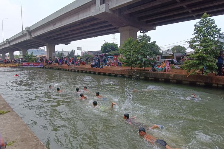 Bocah berenang di aliran Kalimalang di tengah lomba 17 Agustus-an bertajuk Semarak Kalimalang, Cipinang Melayu, Makasar, Jakarta Timur, Minggu (20/8/2023).