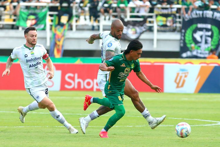 Pemain Persebaya Ripal Wahyudi (hijau) dibayangi dua pemain Persib David da Silva dan Marc Klok, dalam pertandingan pekan ke-15 Liga 1 2023-2024 antara Persebaya vs Persib, Sabtu (7/10/2023) di Stadion Gelora Bung Tomo Surabaya. 
