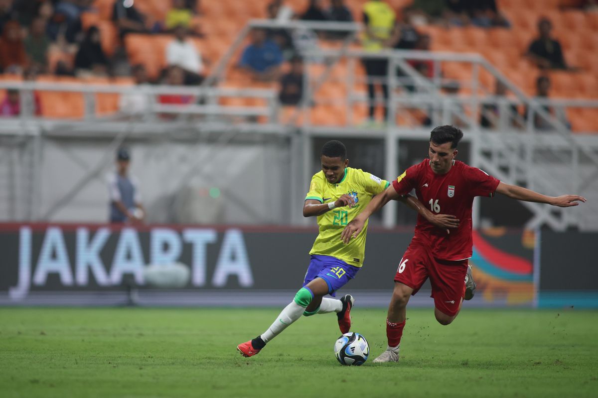 Penyerang timnas U17 Brasil, Estevao Willian (kiri), berebut bola dengan gelandang timnas U17 Iran, Abolfazl Zamani. Laga Brasil vs Iran pada matchday pertama Grup C Piala Dunia U17 2023 tersebut digelar di Jakarta International Stadium (JIS), Sabtu (11/11/2023) malam WIB.