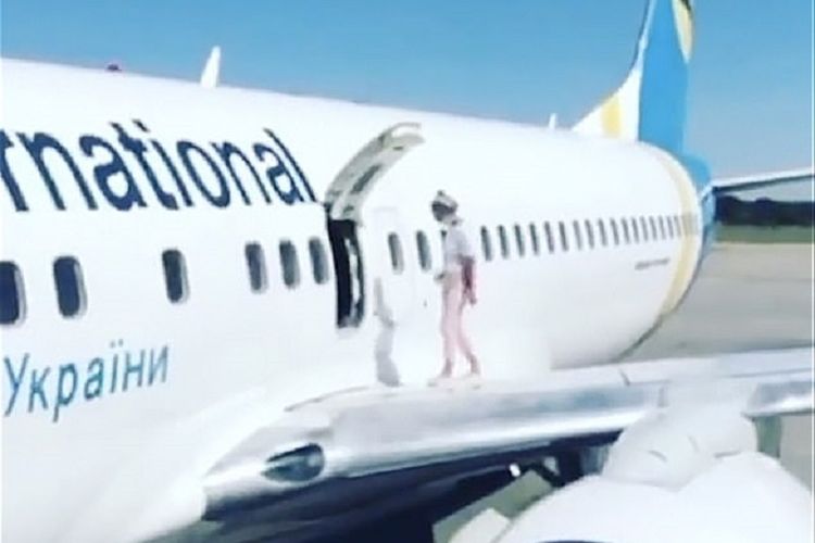 Tangkapan layar di video memperlihatkan seorang ibu berjalan di sayap pesawat Boeing 737-86N milik maskapai Ukraina Ukraine International Airlines, setelah dia membuka pintu darurat karena kepanasan.