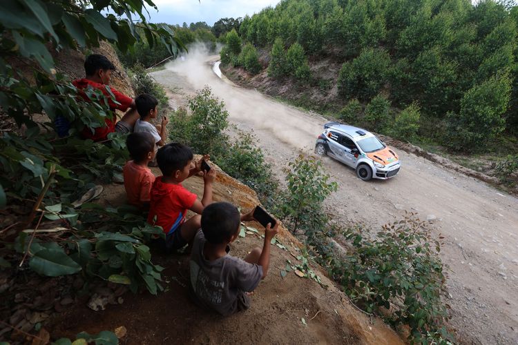 Warga menyaksikan Kejuaraan Nasional  Danau Toba Rally 2022 putaran pertama di kawasan Hutan Tanaman Industri Toba Pulp Lestari, Parapat, Kabupaten Simalungun, Sumatera Utara, Sabtu (6/8/2022). Ryan Nirwan dari Toyota Gazoo Racing memimpin klasemen sementara hingga Special Stage 6.