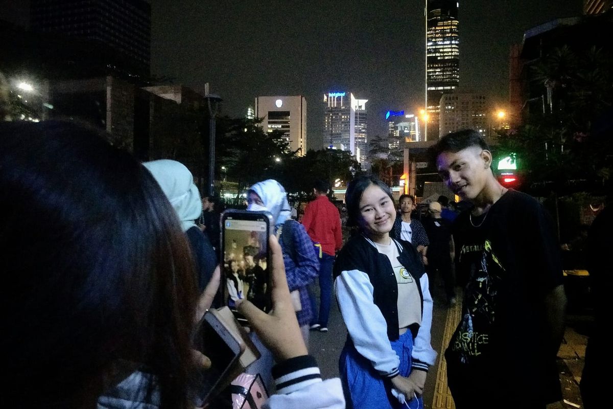 Dirga (16) remaja asal Tanah Abang (kanan) saat diajak berfoto bersama pengunjung Citayam Fashion Week di kawasan berorientasi transit Dukuh Atas, Jakarta Pusat, Senin (25/7/2022) malam.