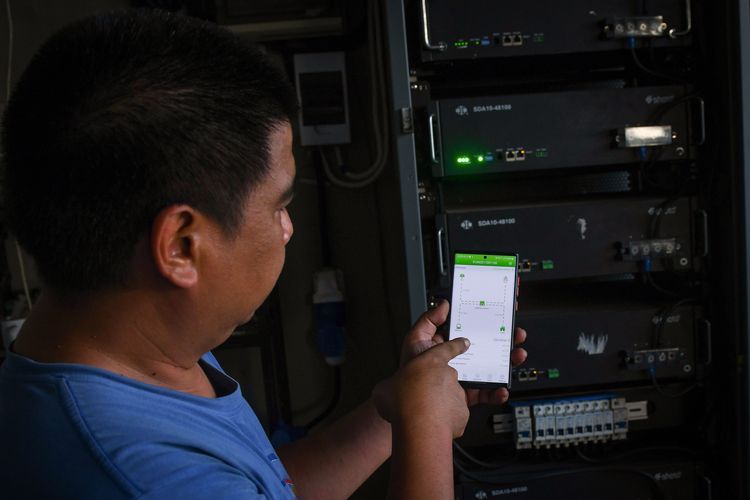 Riky menunjukkan cara memantau dan mengontrol sistem PLTS atap miliknya melalui telepon pintar di Duren Sawit, Jakarta Timur, DKI Jakarta.