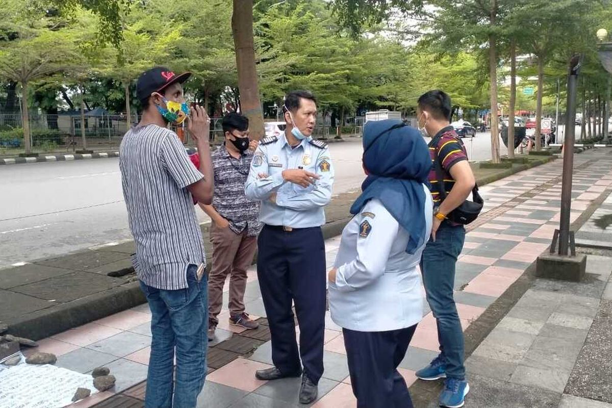 Sudanese refugee, Yusuf (left), is approached by personnel from the Immigration Detention Center after setting up a temporary tent for days in front of the UNHCR building in Makassar on Tuesday, December 22, 2020.  