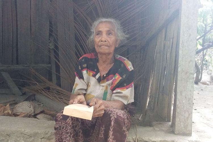 Foto : Nenek Paulina Poing (79), warga Dusun Gehak Reta, Desa Koting D, Kecamatan Koting, Kabupaten Sikka, Flores, Nusa Tenggara Timur, duduk di depan gubuknya sambil memegang amplop berisi uang dari Presiden Joko Widodo, Minggu (20/10/2019).