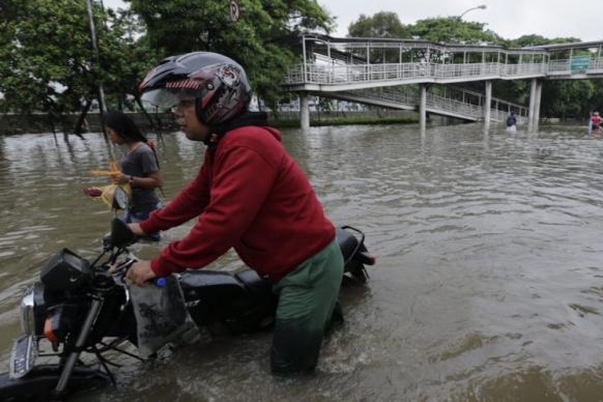 Warga menggunakan sepeda motor berupaya menerobos banjir di Jalan Perintis Kemerdekaan, Pedongkelan, Jakarta, Senin (9/2/2015). Curah hujan yang tinggi mengakibatkan sejumlah tempat di ibu kota terendam banjir.