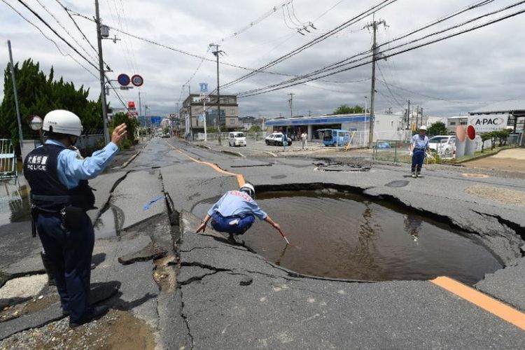 Polisi memeriksa jalan yang retak menyusul gempa di Takatsuki, sebelah utara Osaka, Jepang, Senin (18/6/2018). (AFP/STR/Jiji Press)