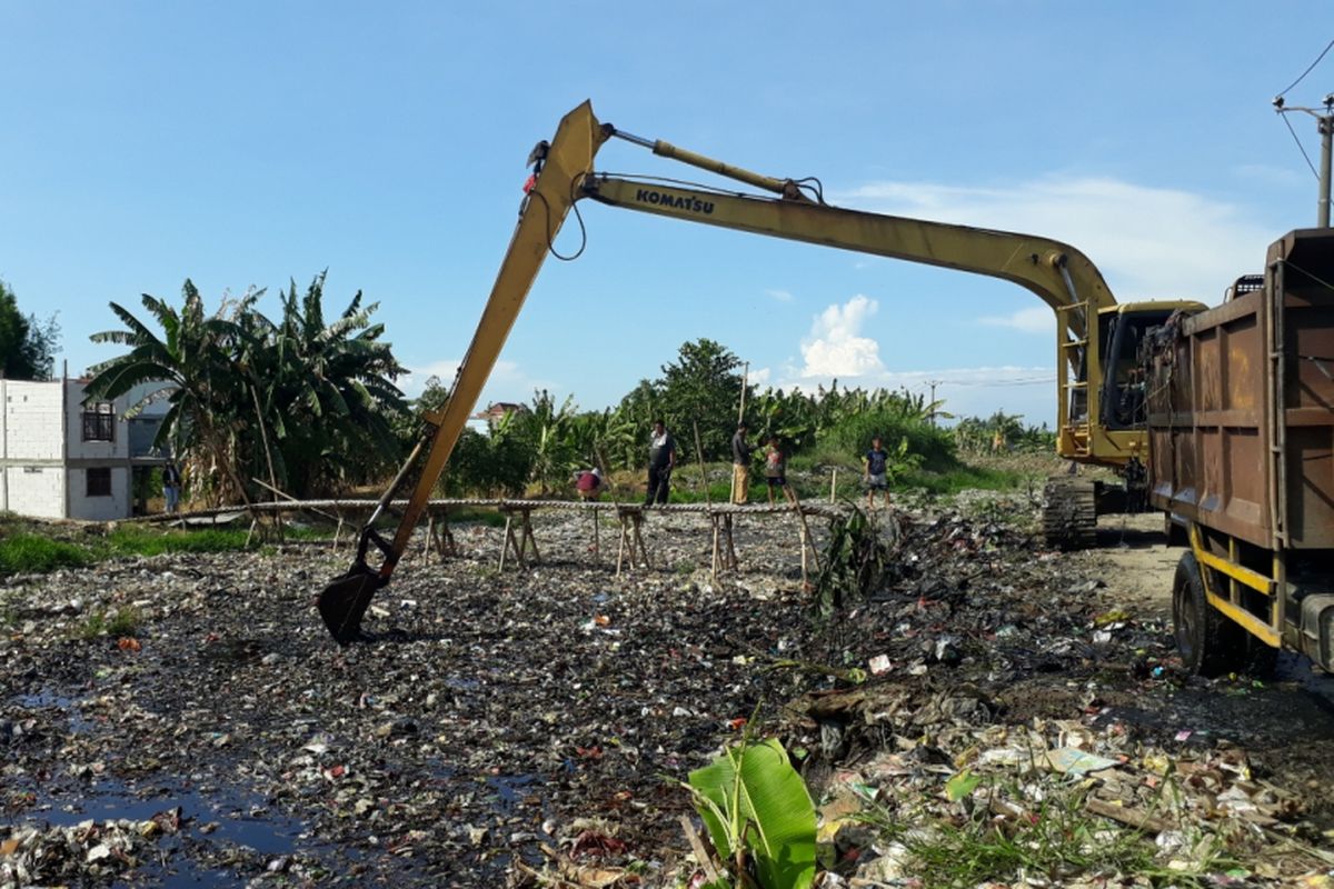Alat berat angkut sampah di Kali Pisang Batu, Desa Pqhlawan Setia, Tarumajaya, Kabupaten Bekasi, Senin (7/1/2019).