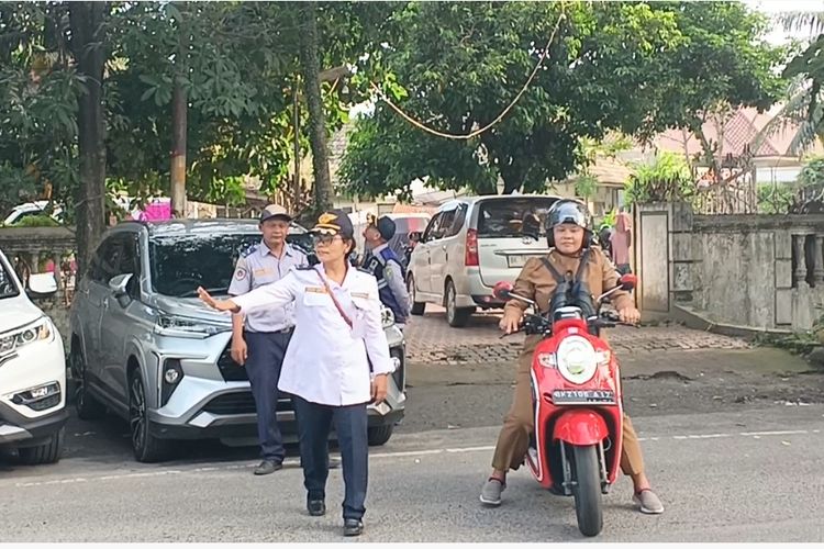 Petugas Dishub Kota Medan menyeberangkan pengendara motor yang baru saja membeli stiker parkir berlangganan di Jalan Samanhudi, Kota Medan, Senin (1/7/2024)