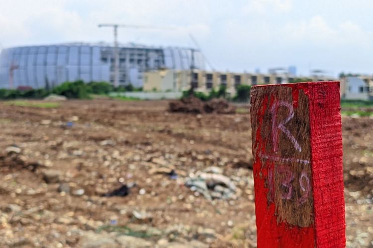 Patok penanda lintasan Formula E Jakarta berlatar tanah kosong penuh sampah dan bangunan Jakarta Internasional Stadium, Rabu (29/12/2021)