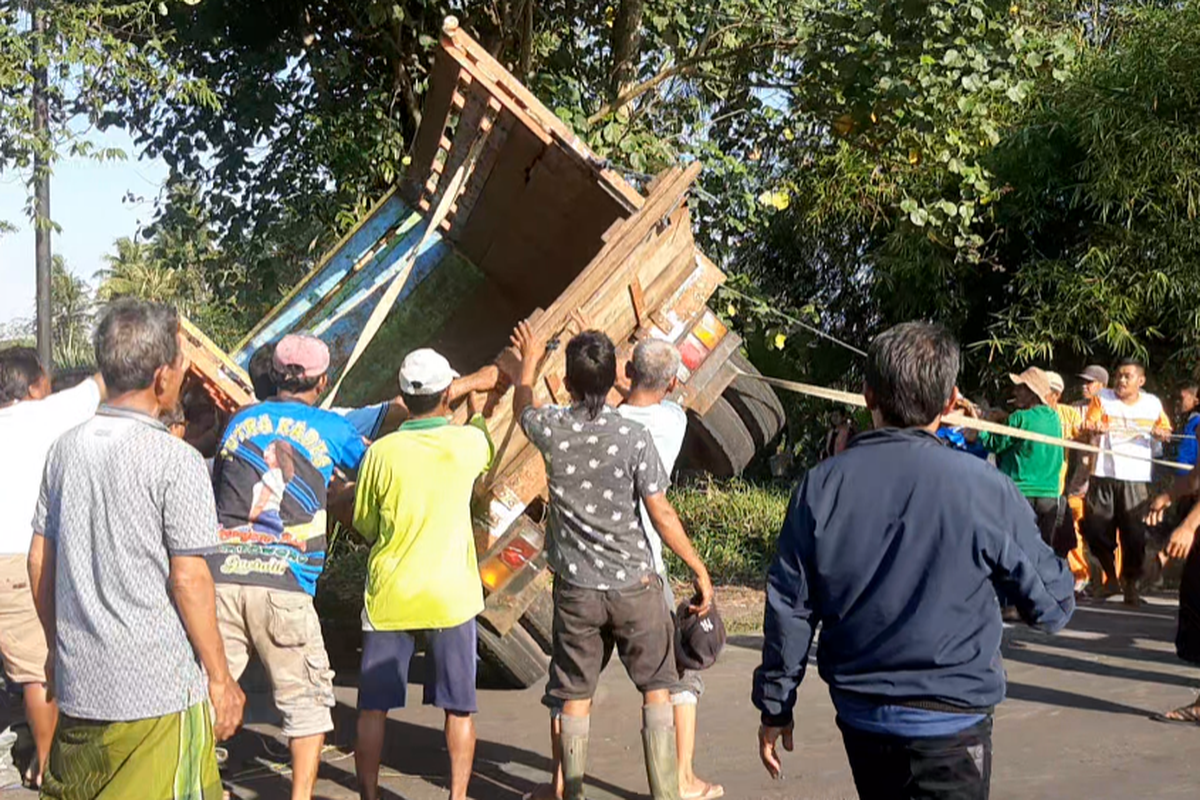 Warga bergotong royong mengevakuasi truk yang terguling di JLT Lumajang, Minggu (12/3/2023)