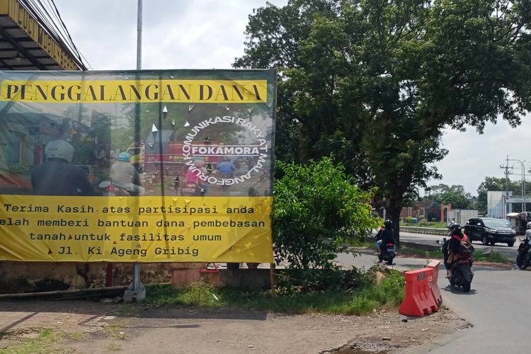 Banner besar di Jalan Raya Ki Ageng Gribig menuju Exit Tol Madyopuro pada Jumat (8/4/2022) soal pembebasan sebagian lahan tempat cucian mobil.