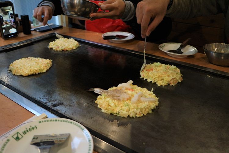 Proses memanggang okonomiyaki, bagian ekor udang diletakkan mencuat, Sabtu (21/1/2023).