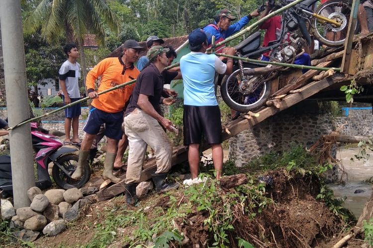 Warga Dusun Bangbayang memindahkan motor mereka menyeberangi Sungai Ciawi untuk di simpan di Kampung Babakan yang ada di seberang sungai agar bisa tetap beraktivitas ke luar dusun, Kamis (23/09/2022)