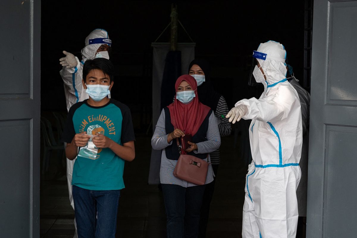 Petugas medis mengenakan APD mempersilakan orang-orang masuk untuk menjalani tes Covid-19 di Shah Alam, pinggiran Kuala Lumpur, Malaysia, pada 17 Februari 2021.