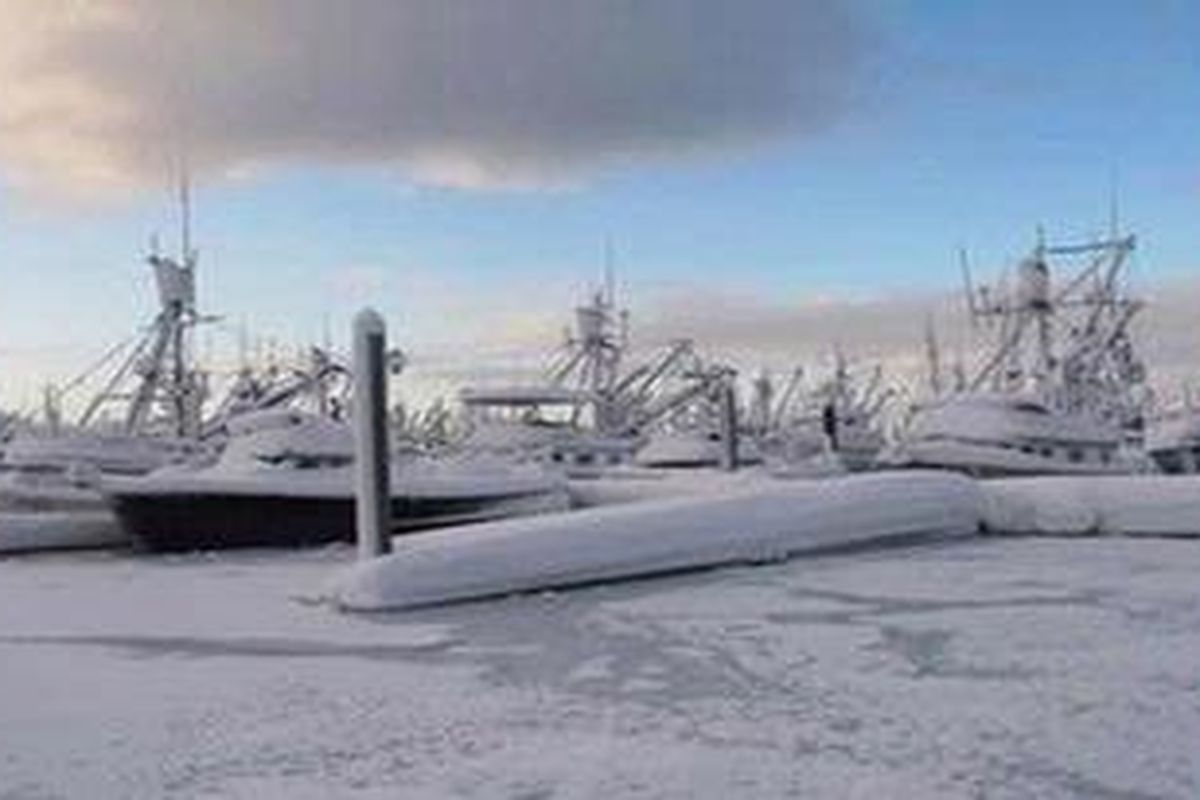 Salju menyelimuti perahu-perahu di pelabuhan Cordova, Alaska, yang membeku terkena musim dingin ekstrem pekan ini.  
