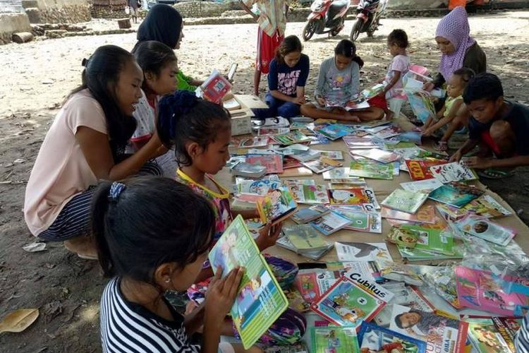 Beberapa orang anak tampak serius membaca buku kesukaannya saat Rumah Baca Barakate, Komunitas Hikayat Tanah Hitu, membuka lapak baca di sebuah tanah lapang di Desa Hitu Mesing, Kecamatan Leihitu, Kabupaten Maluku Tengah, Minggu, (30/5/2017).