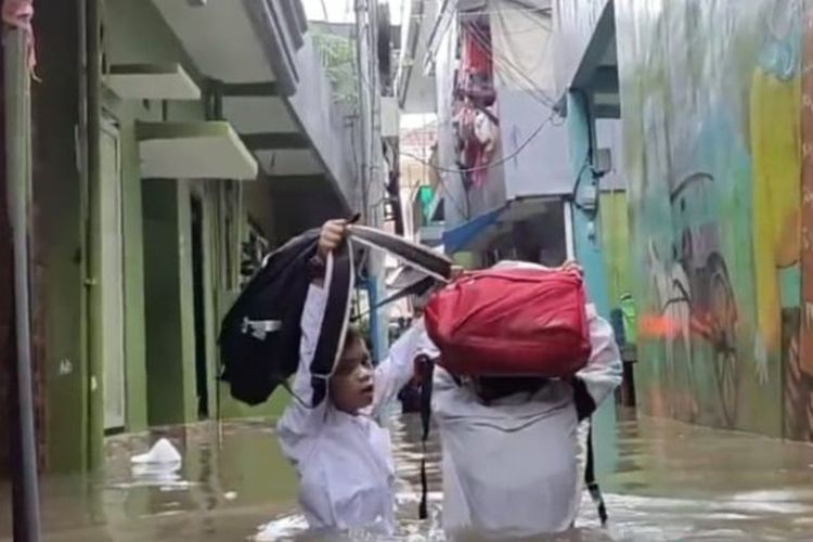 Dua orang siswa sekolah dasar (SD) tengah melintasi banjir di permukiman Kebon Pala, Kelurahan Kampung Melayu, Kecamatan Jatinegara, Jakarta Timur, Jumat (24/2/2023). 