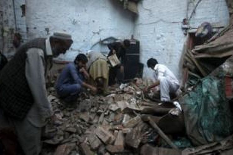 Para warga sedang mencari barang milik mereka di reruntuhan sebuah rumah yang hancur karena gempa bumi di Peshawar, Pakistan. 