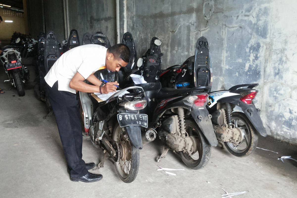 Seorang petugas mengecek motor-motor yang ditarik dan disimpan di gudang penyimpanan milik Adira Finance di Tapos, Depok, Senin (5/2/2018).