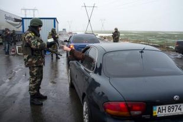 Seorang personel militer Ukraina tengah memeriksa seorang pengemudi di sebuah pos penjagaan tak jauh dari kota Donetsk, kubu terkuat pemberontak pro-Rusia.