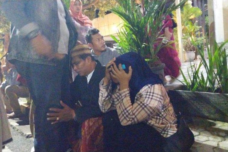 Seorang pria terlihat duduk bersisian dengan seorang wanita, dan keduanya menangis. Mereka duduk di trotoar dekat kendaraan-kendaraan besar yang tengah terparkir di area Pelabuhan Ketapang, Kamis pagi (3/7/2025) menyusul tenggelamnya KMP Tunu Pratama Jaya.

