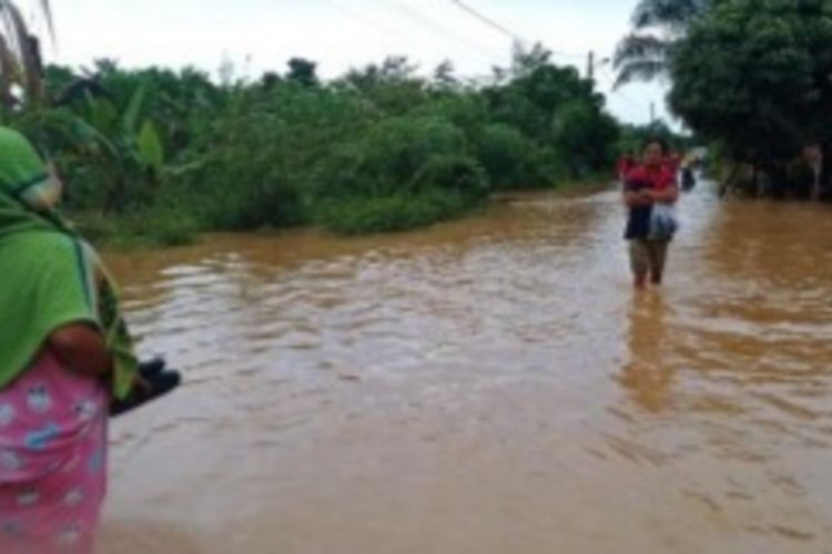 Warga mengarungi genangan banjir di Desa Suka Ramai, Kecamatan Tapung, Kabupaten Kampar, Riau, Senin (27/9/2021).