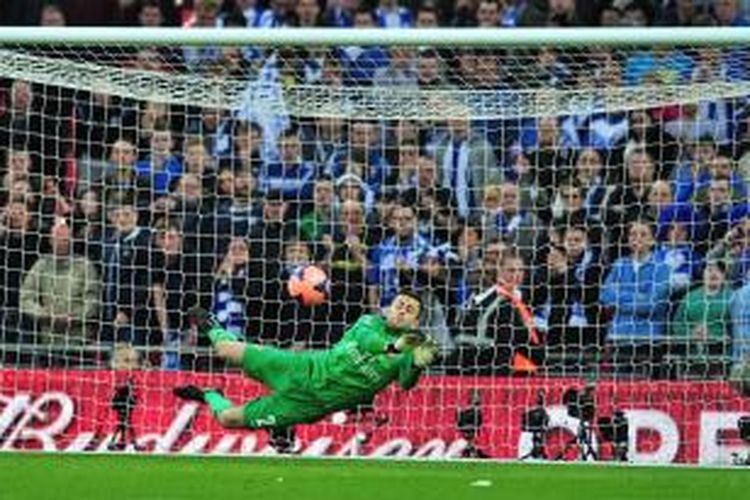 Kiper Arsenal Lukas Fabianski mengantisipasi eksekusi penalti gelandang Wigan Athletic Jack Collison, pada babak adu penalti, semifinal Piala FA, di Wembley, Sabtu (12/4/2014). 